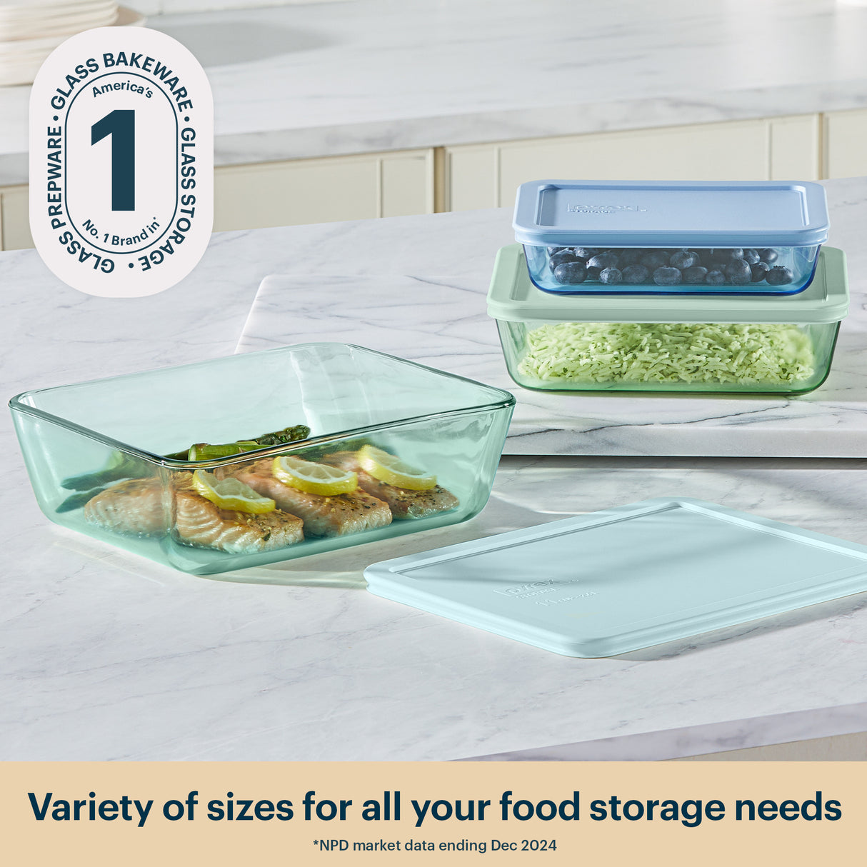 Glass bakeware set with food on a table, featuring a brand logo and text about variety of sizes.