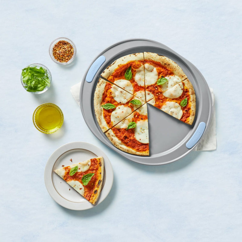 Margherita pizza on a pizza stone with ingredients on a light blue background
