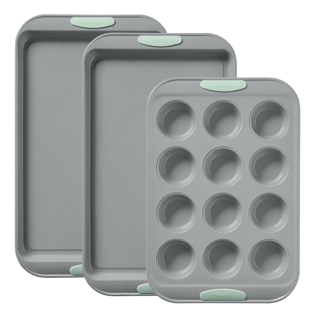Set of three gray baking trays with green silicone grips on a white background