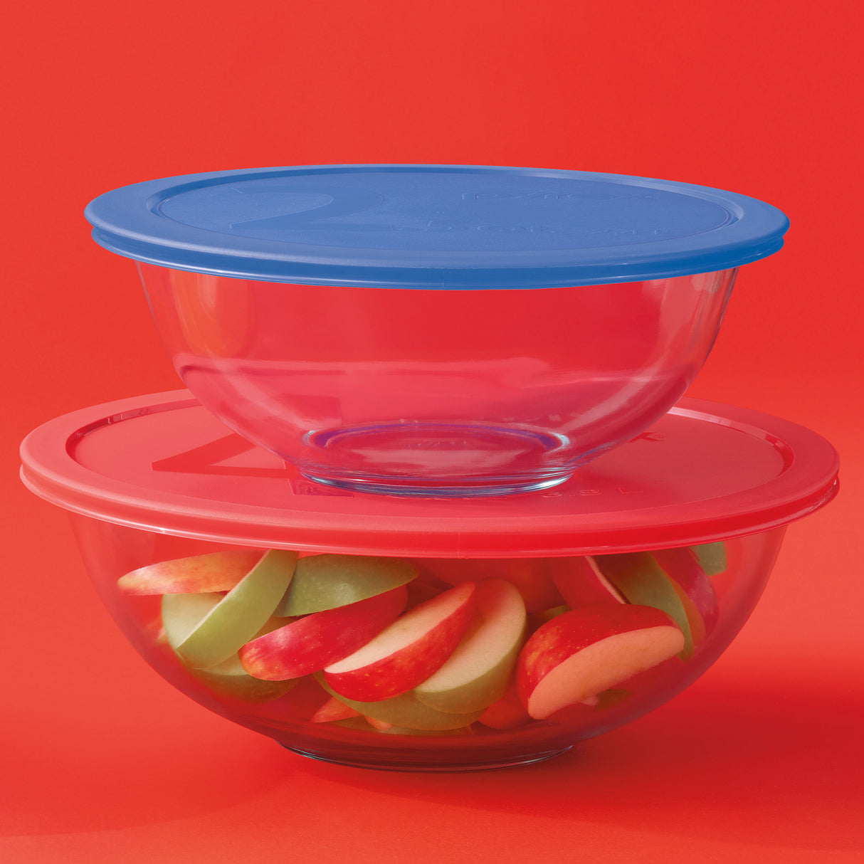 Stack of glass bowls with colorful fruit slices on a red background