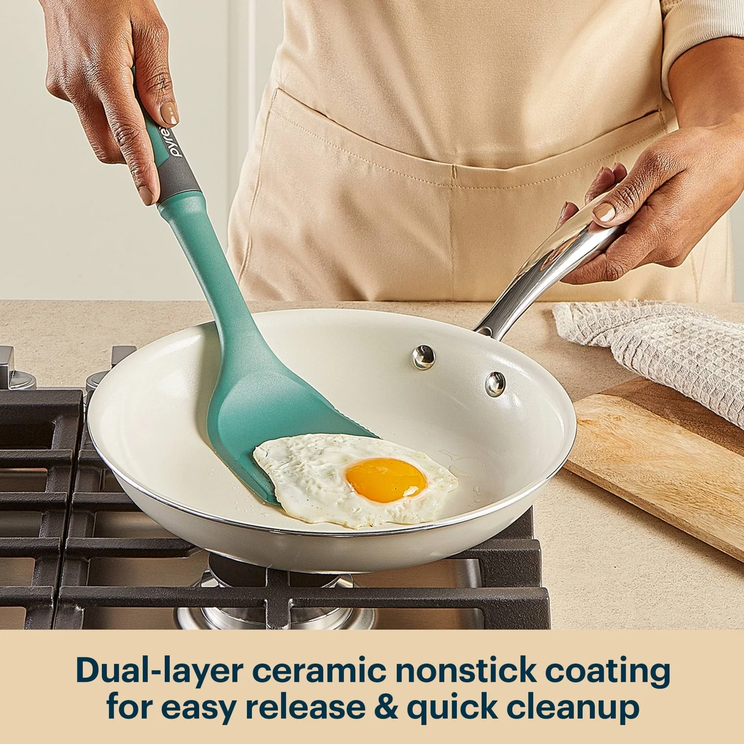 Person cooking an egg in a frying pan with a green spatula, kitchen setting.