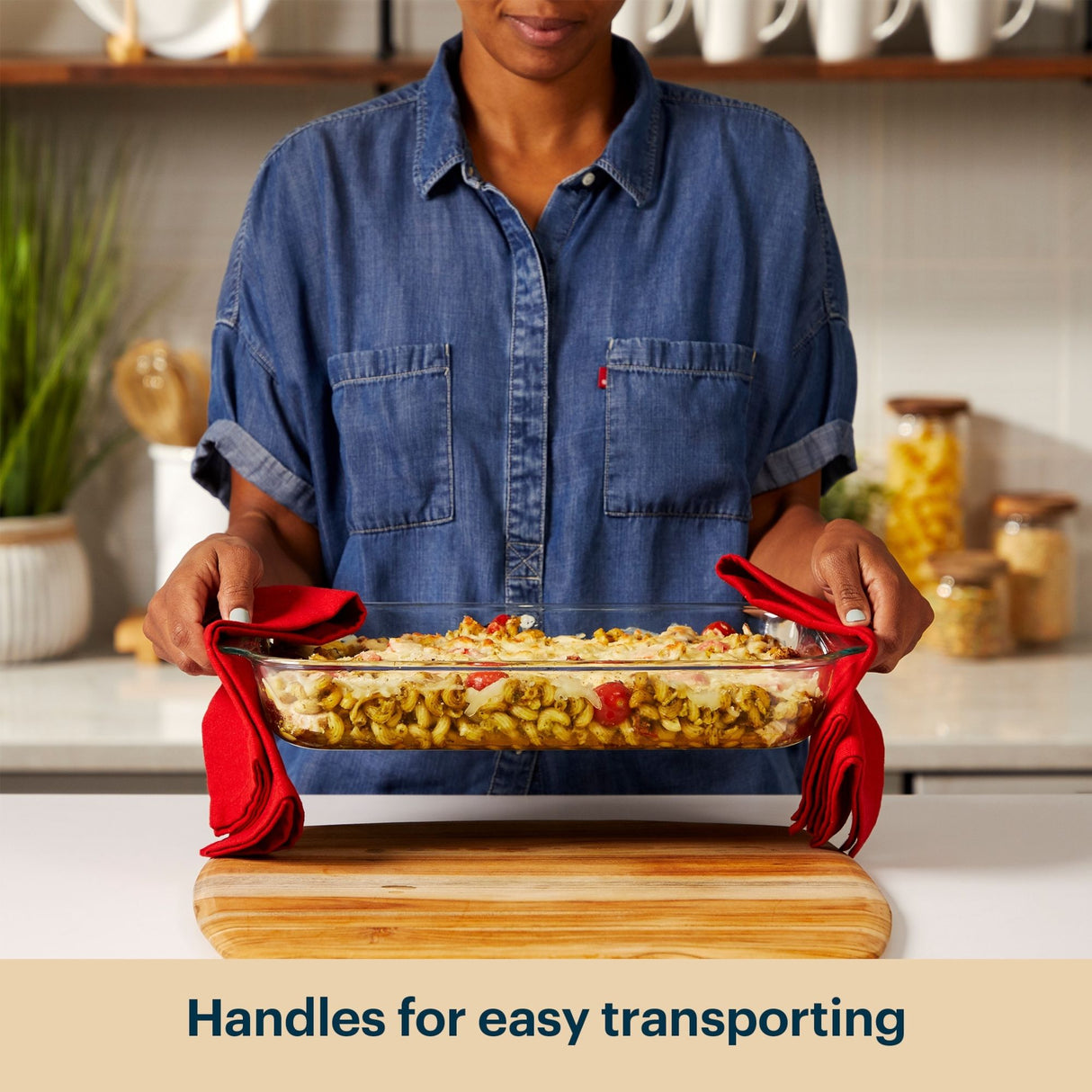 Person holding a dish with red handles in a kitchen setting